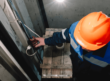 Engineer lubricating lift machinery as part of scheduled maintenance.