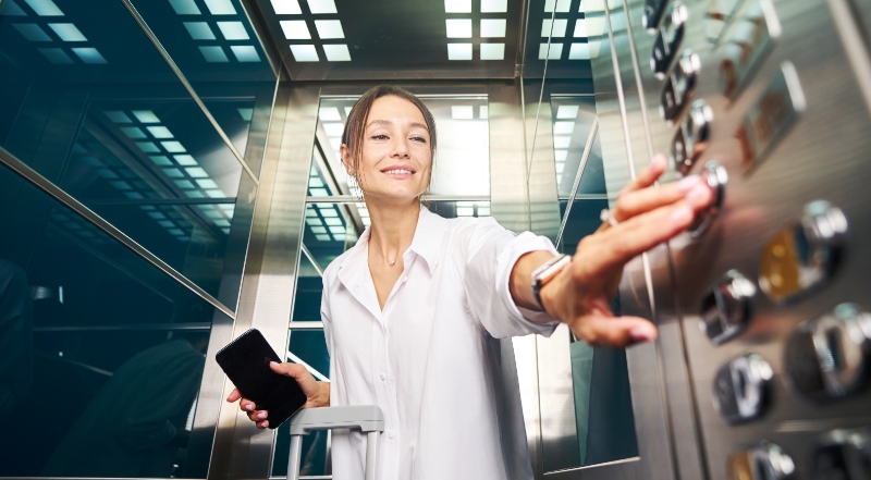 A lady pressing the COP buttons in a glass passenger lift cabin